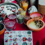 Vibrant collection of handmade candles and decorative stickers on a red tablecloth.